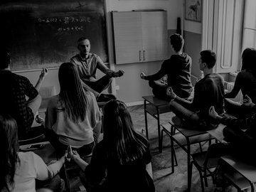 students meditating with teacher in classroom